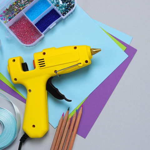 Craft supplies with hot glue gun, paper, and colored pencils